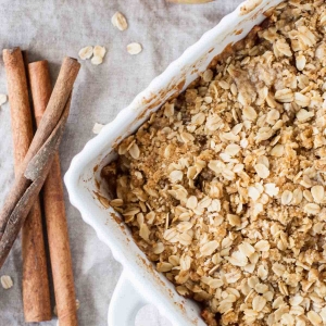 Overhead shot of apple crisp with cinnamon sticks on the side.