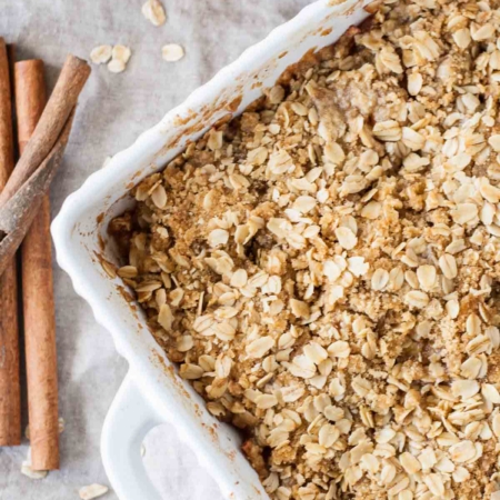 Overhead shot of apple crisp with cinnamon sticks on the side.