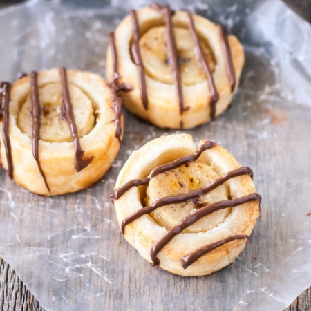 Banana bites drizzled with chocolate on a piece of parchment.