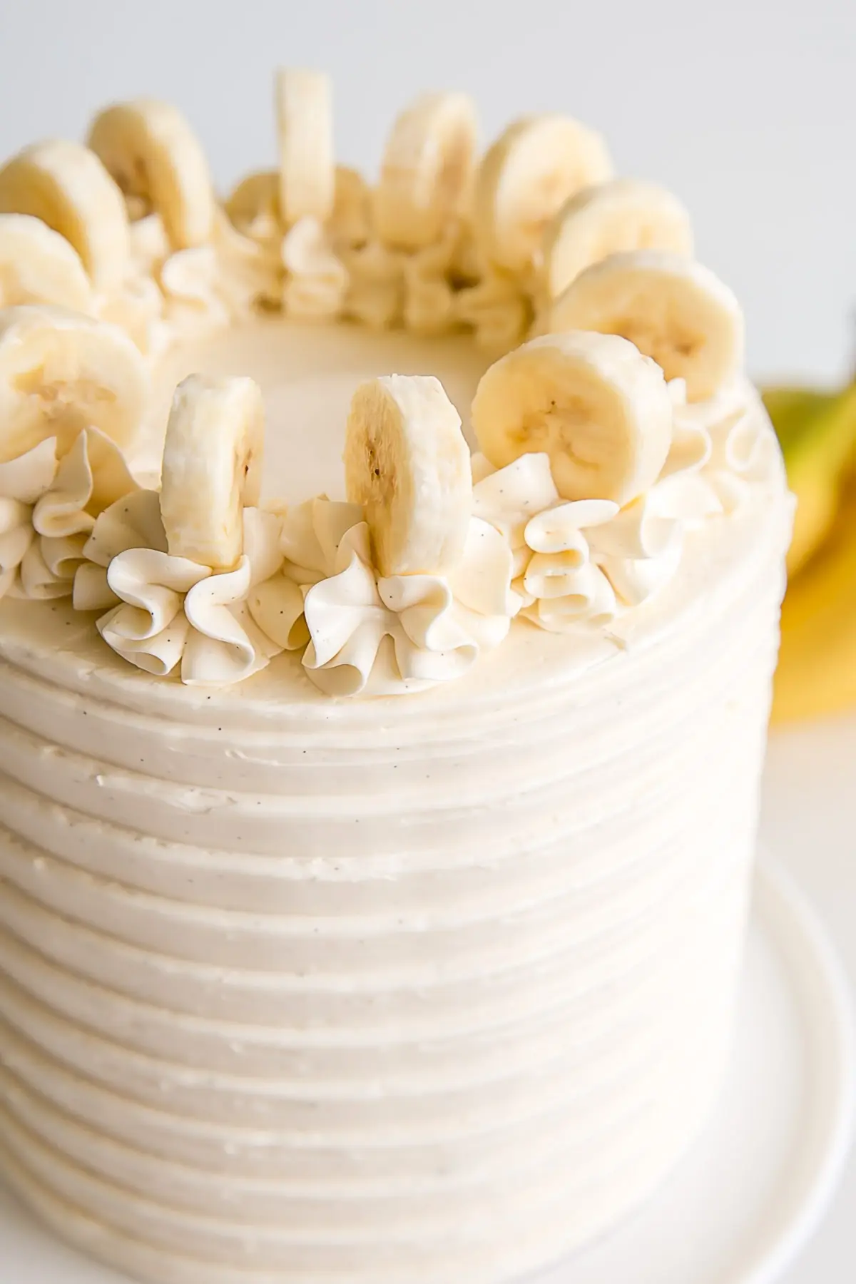 Close up of the top of the cake with rosettes and fresh banana slices.