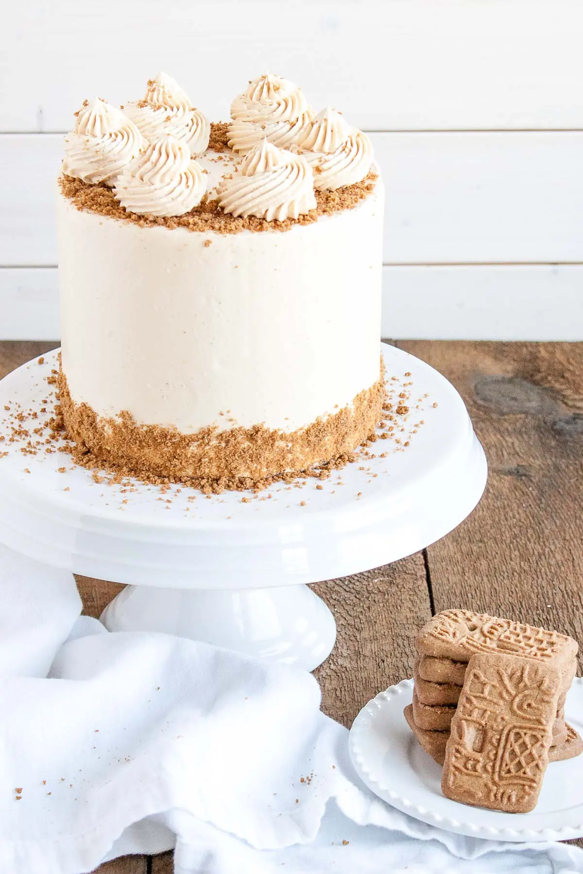 Angled shot of the biscoff cake with speculoos cookies on a plate beside it.