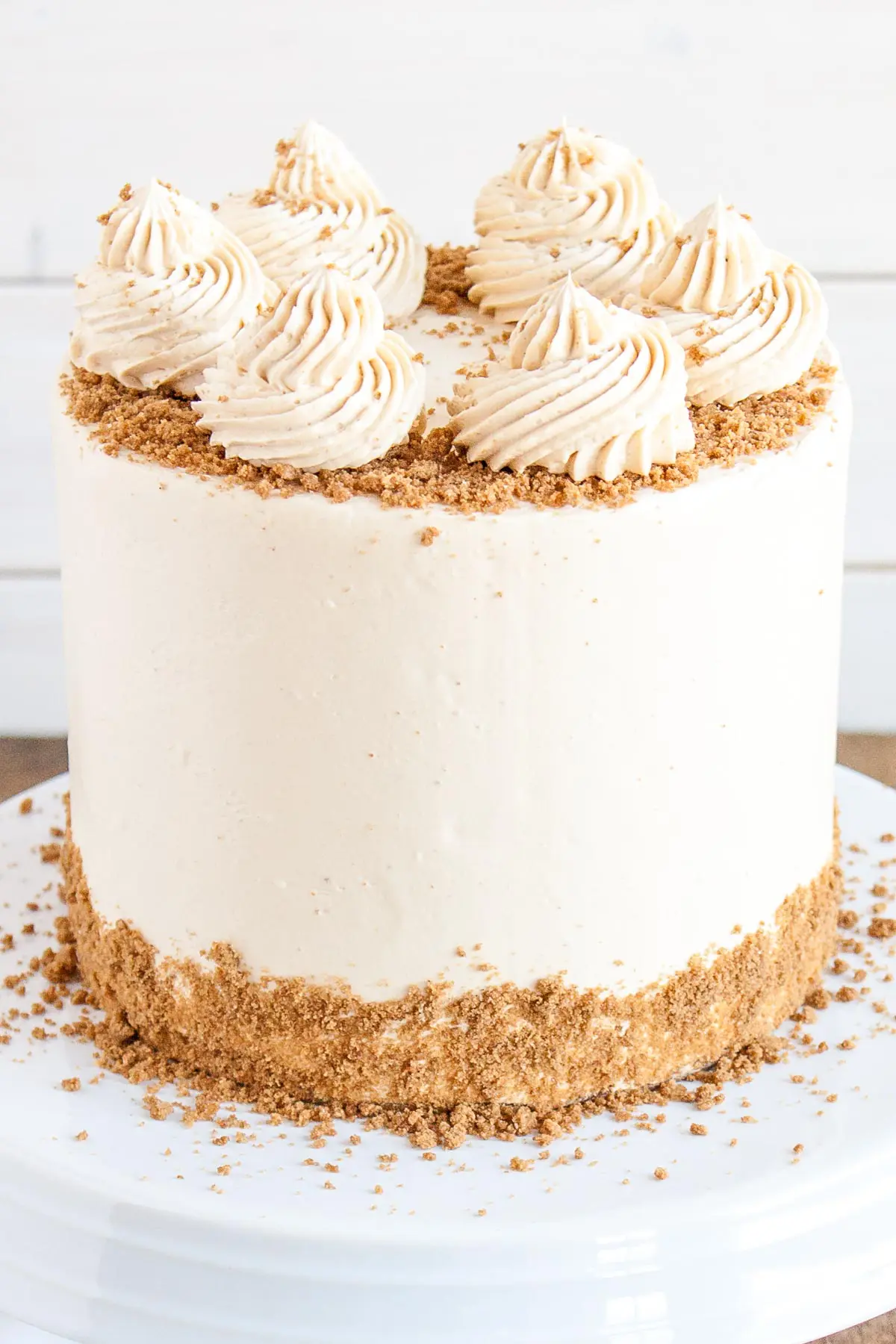 Close up of a cookie butter cake with rosettes on top and crushed speculoos cookies around the edge.