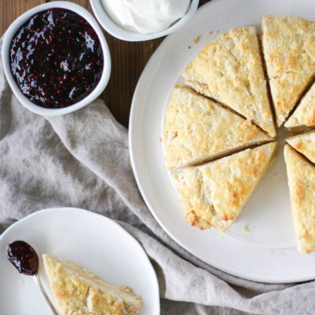 Overhead shot of scones on a plate with a side of jam and cream.