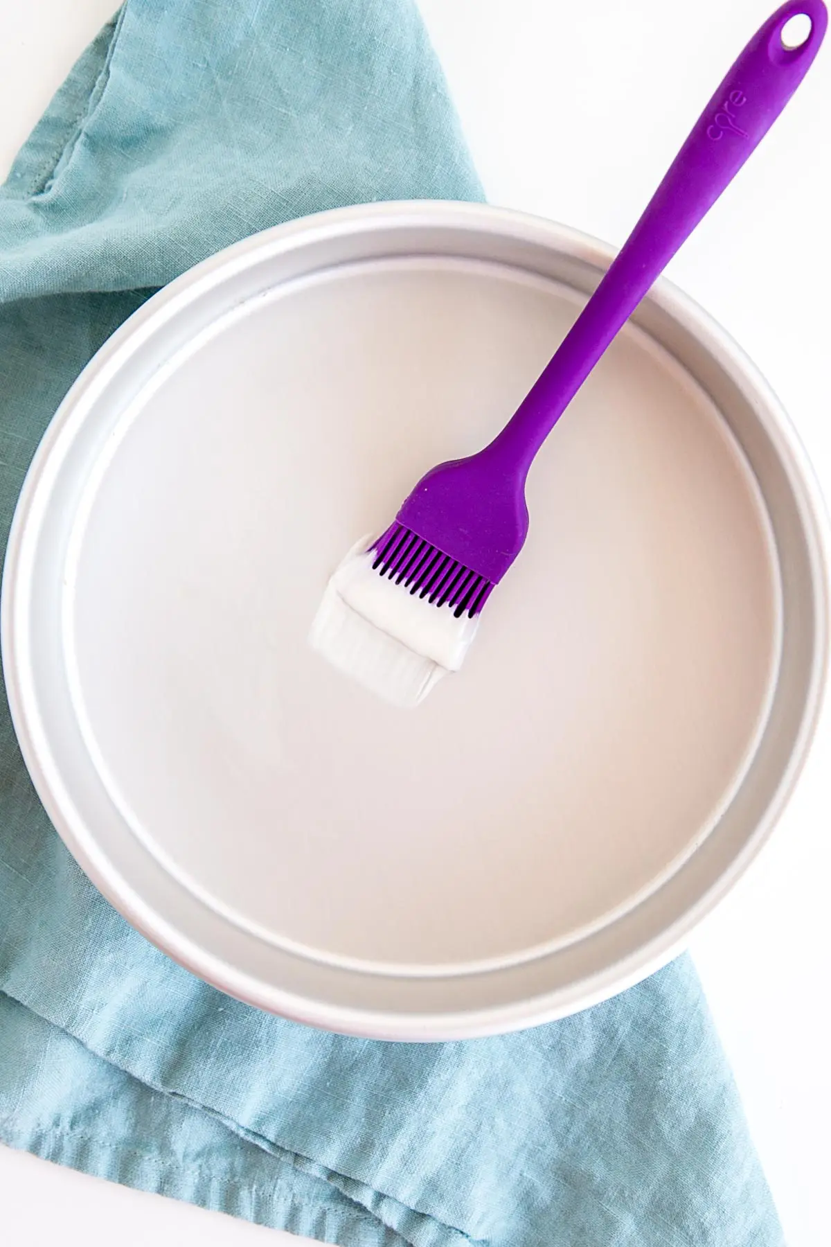 Pastry brush dipped in cake release in a cake pan.