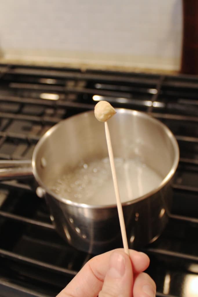 Hazelnut on a skewer with boiling sugar in the background.