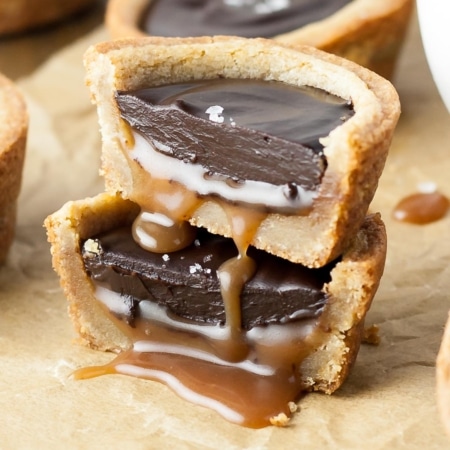 Two cookie cup halves stacked on top of each other with caramel oozing out.