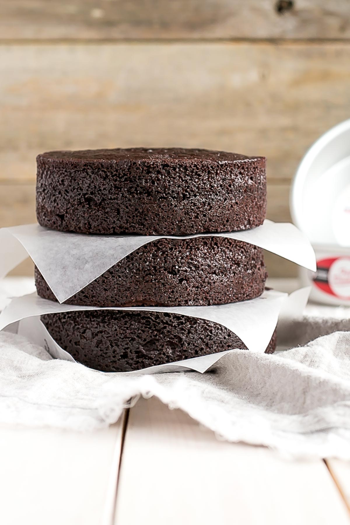 A photo of the cake layers stacked with parchment between.