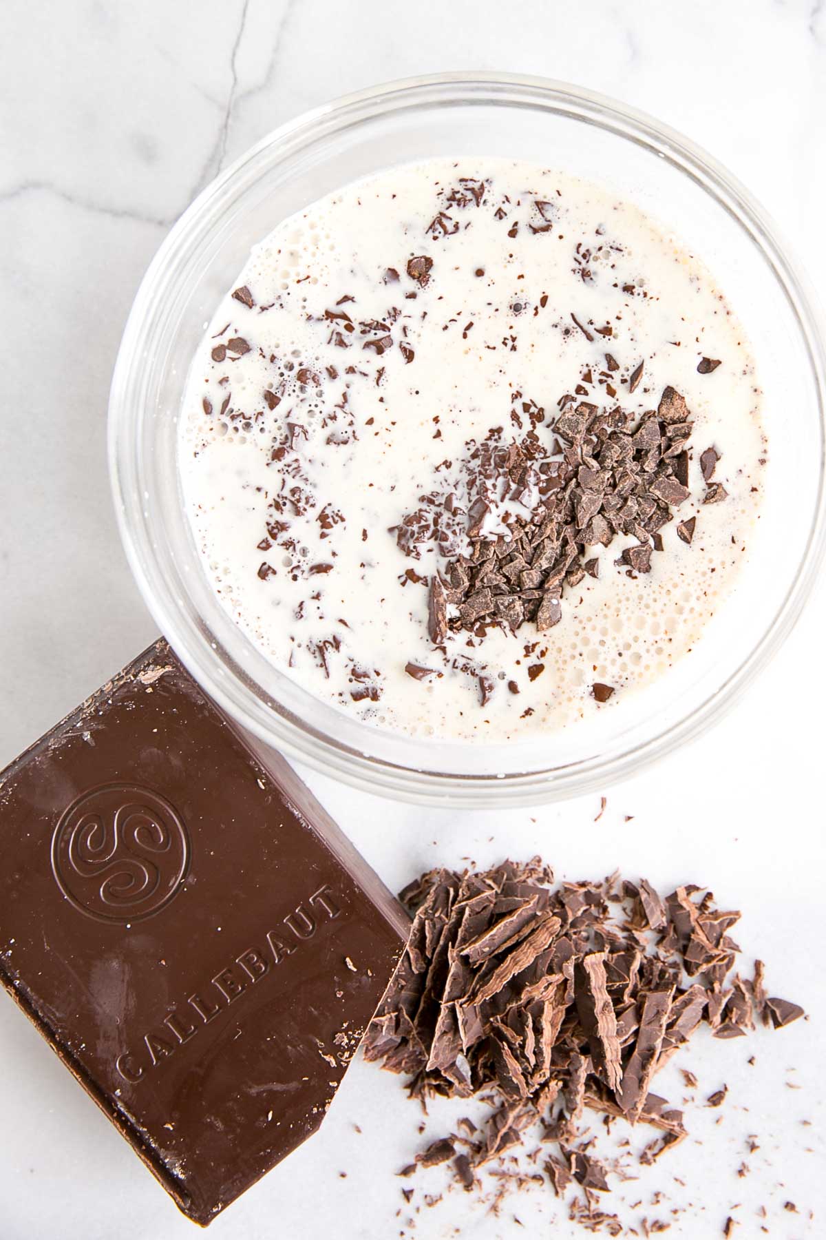 Cream poured over chopped chocolate in a glass bowl.