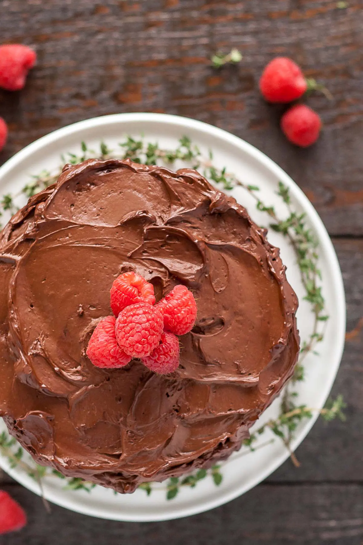 Overhead shot of the chocolate covered cake with raspberries on top.