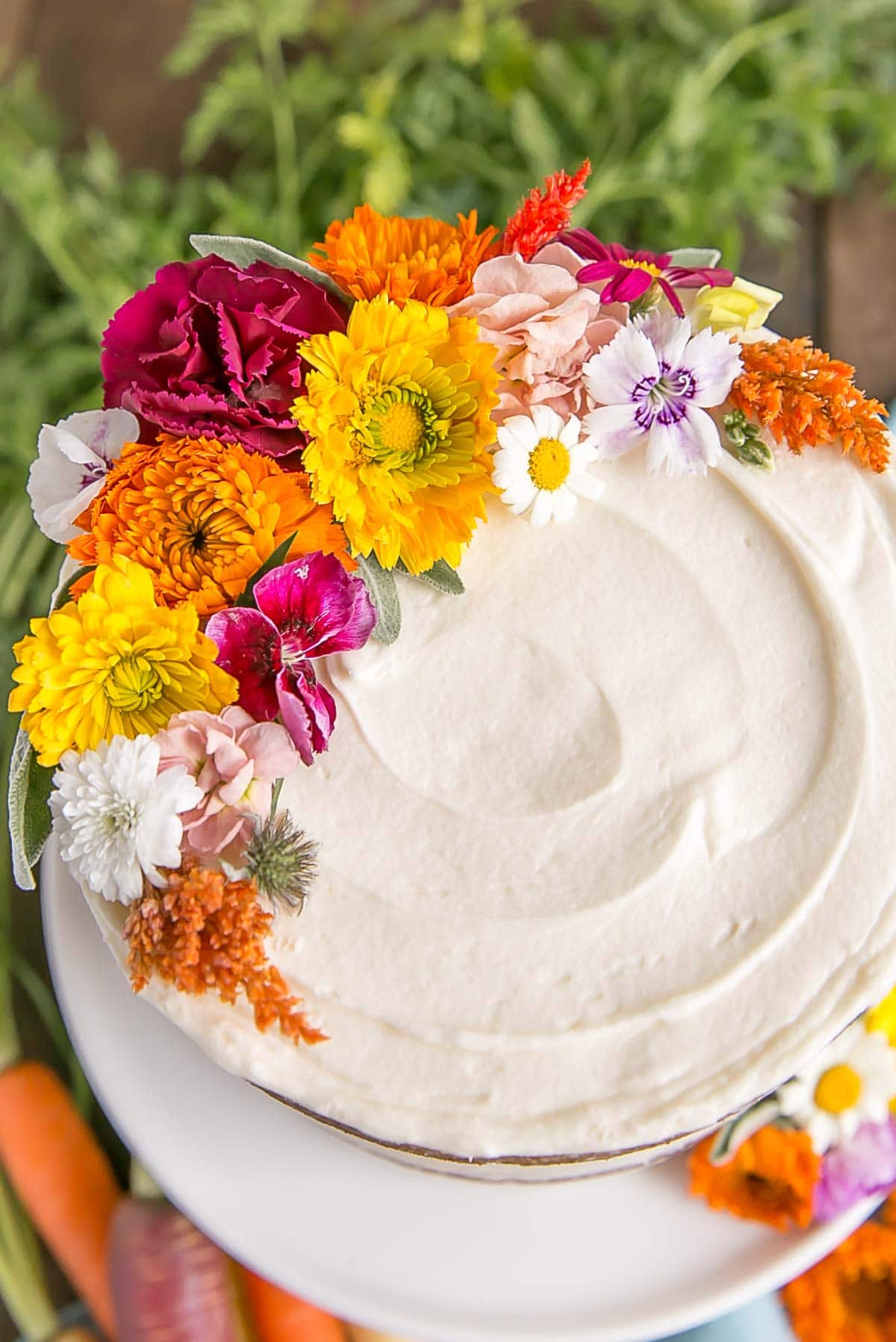 Close up of edible flowers on carrot cake with cream cheese frosting.