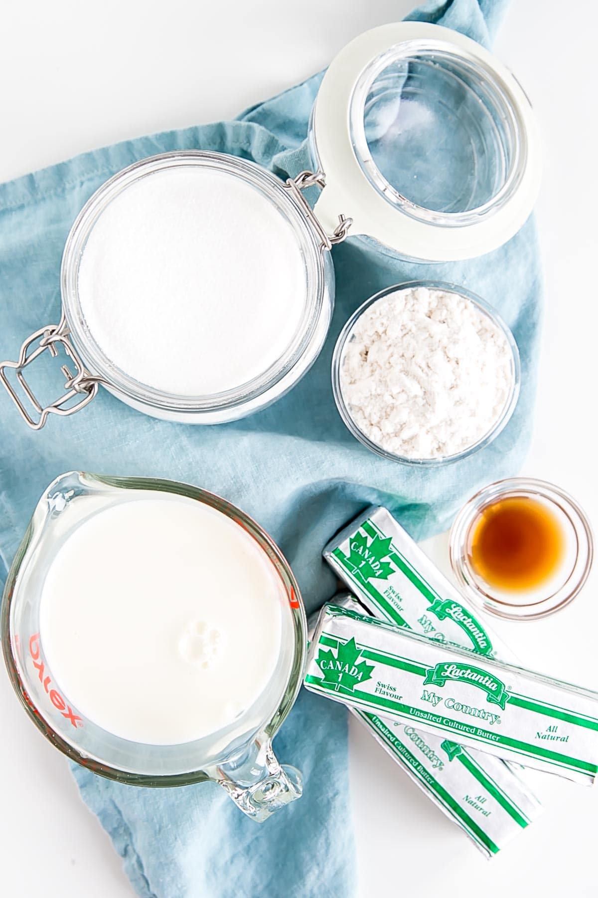 Ingredients shown against a blue tea towel -- milk, sugar, flour, butter, and vanilla.