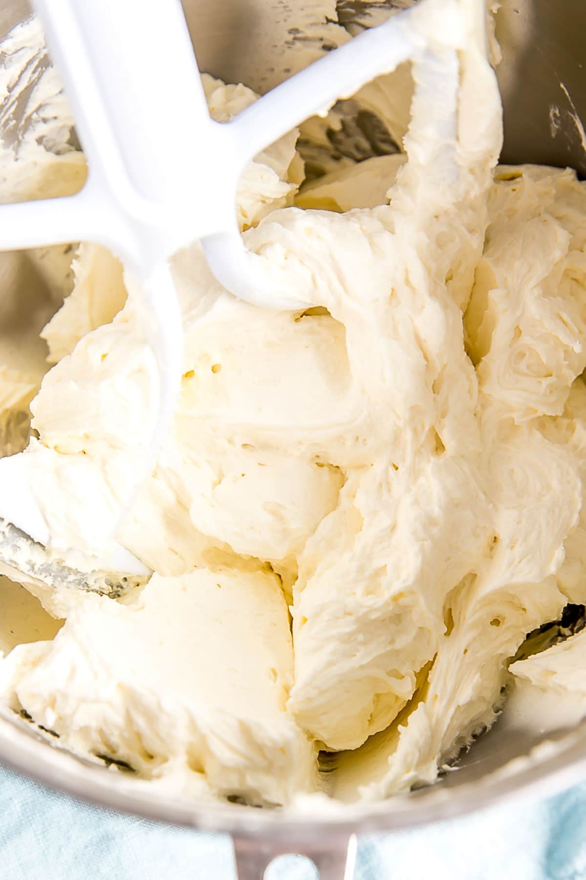 Light and fluffy buttercream in the bowl of a stand mixer.