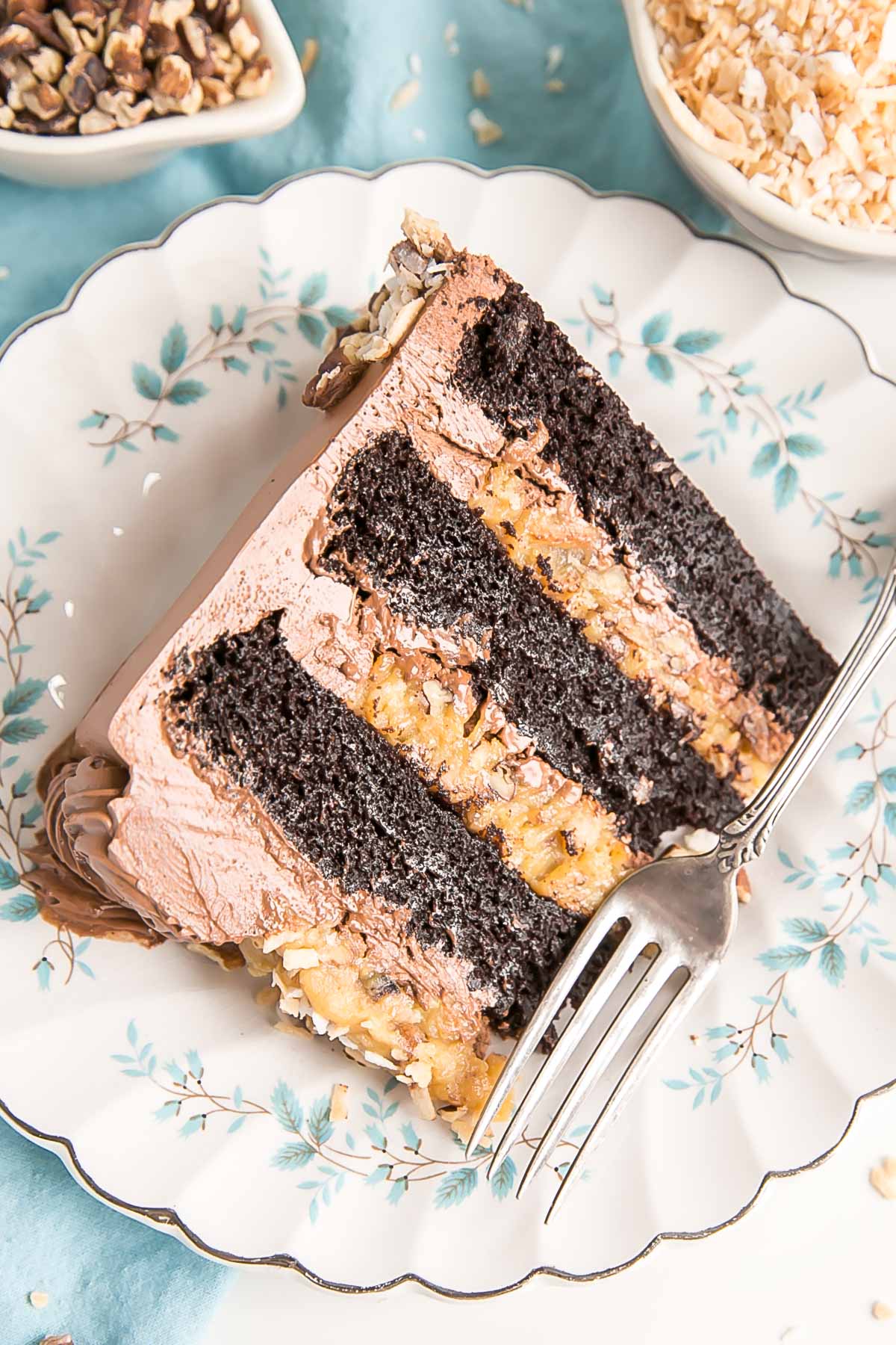 Slice of cake on a blue flower plate with a blue cloth under it.