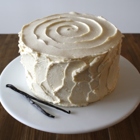 A cake on a white cake stand sitting on top of a wooden table