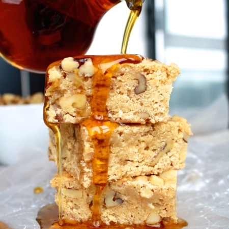 Stack of maple bars with maple syrup being drizzled on top.