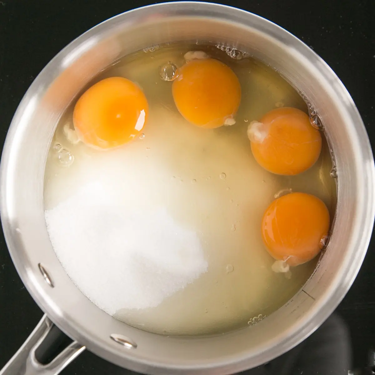 Eggs and sugar in a pot.