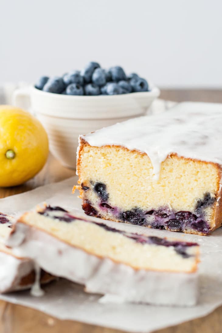 Cut loaf with a bowl of blueberries beside it.