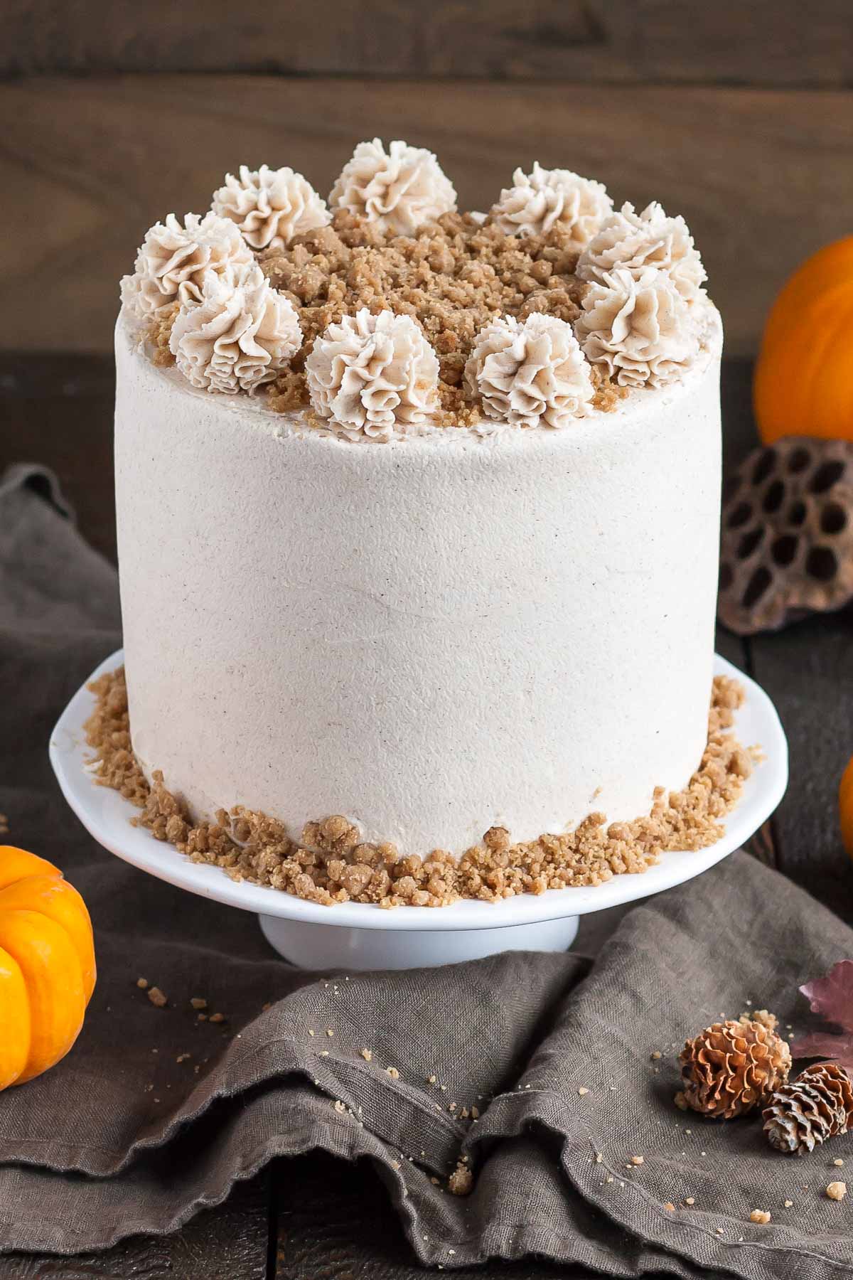 Cake on a cake stand with fall decor in the background.