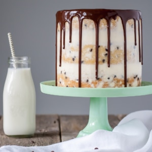 Cake on a green cake stand with a glass of milk beside it.