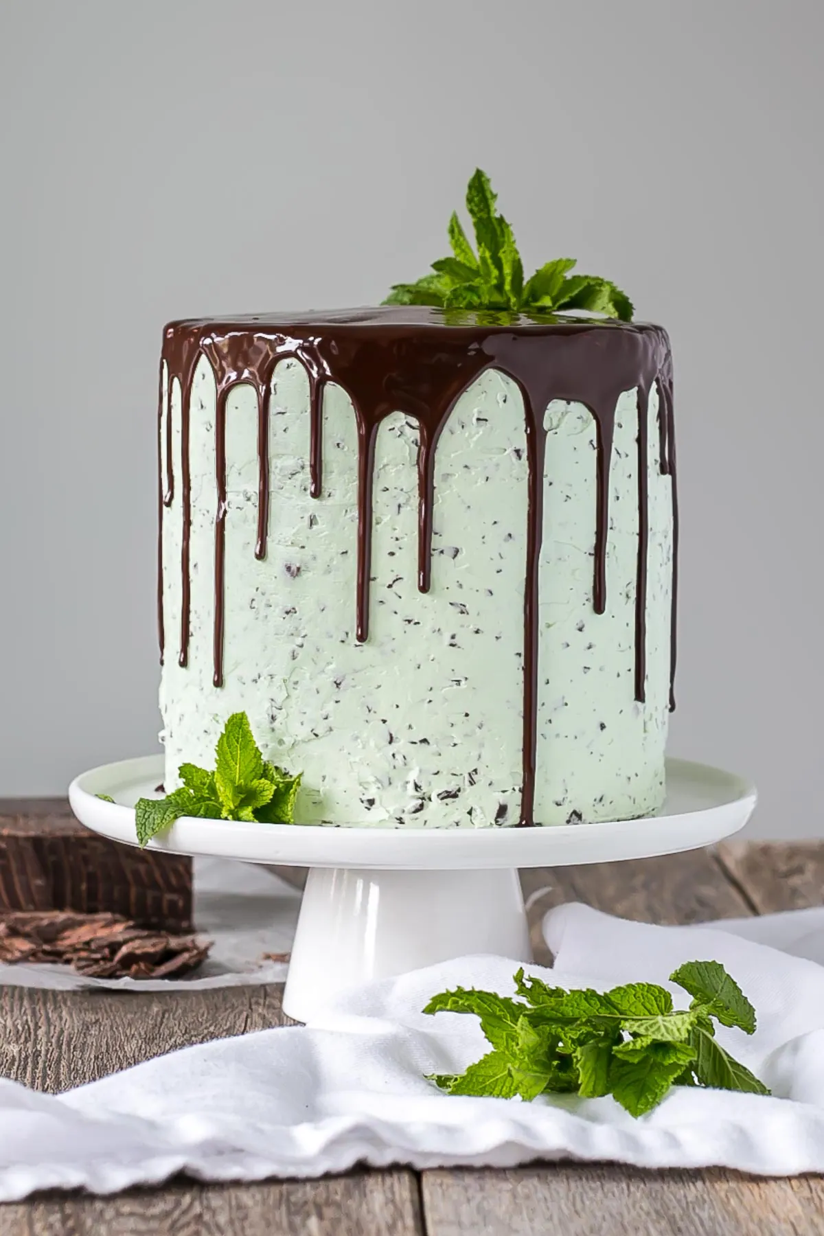 Cake on a white cake stand with mint garnish.