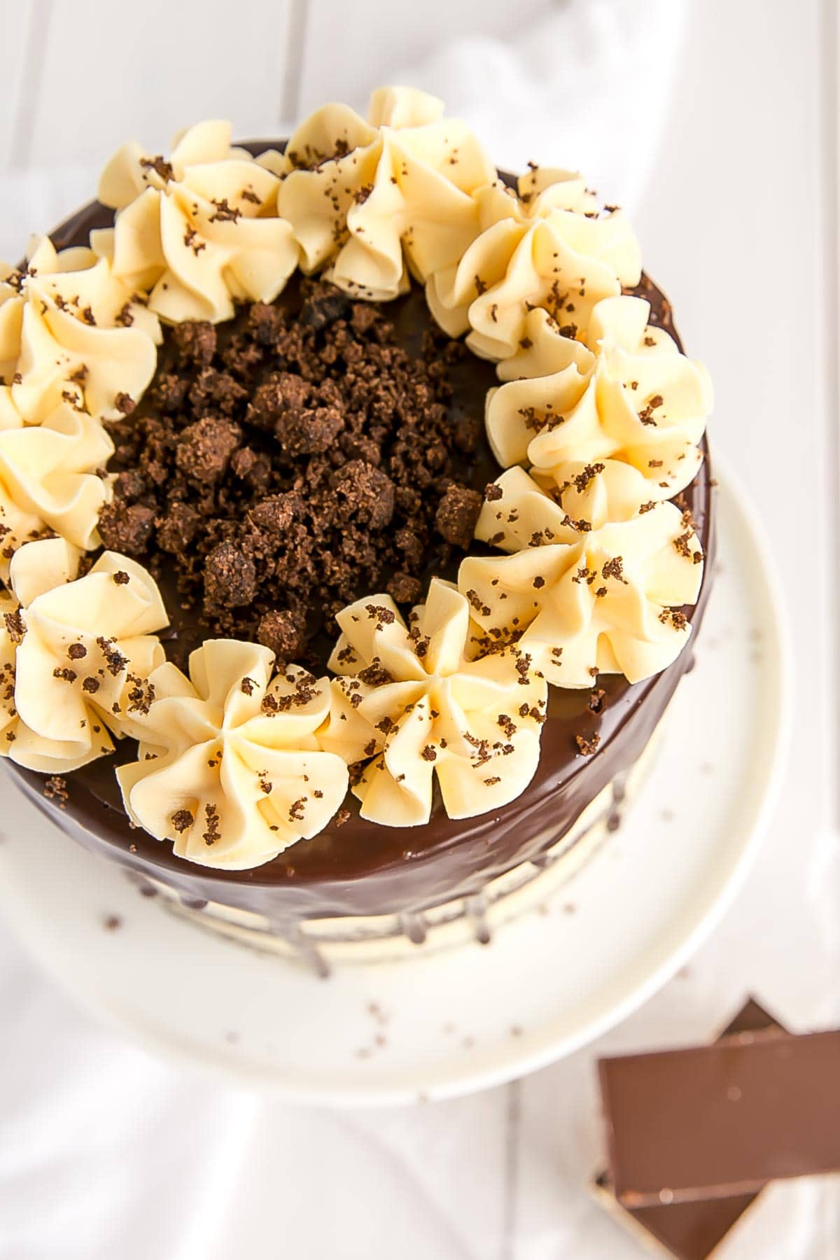 Nanaimo bar cake from the top with ruffle dollops and a cookie crumble.