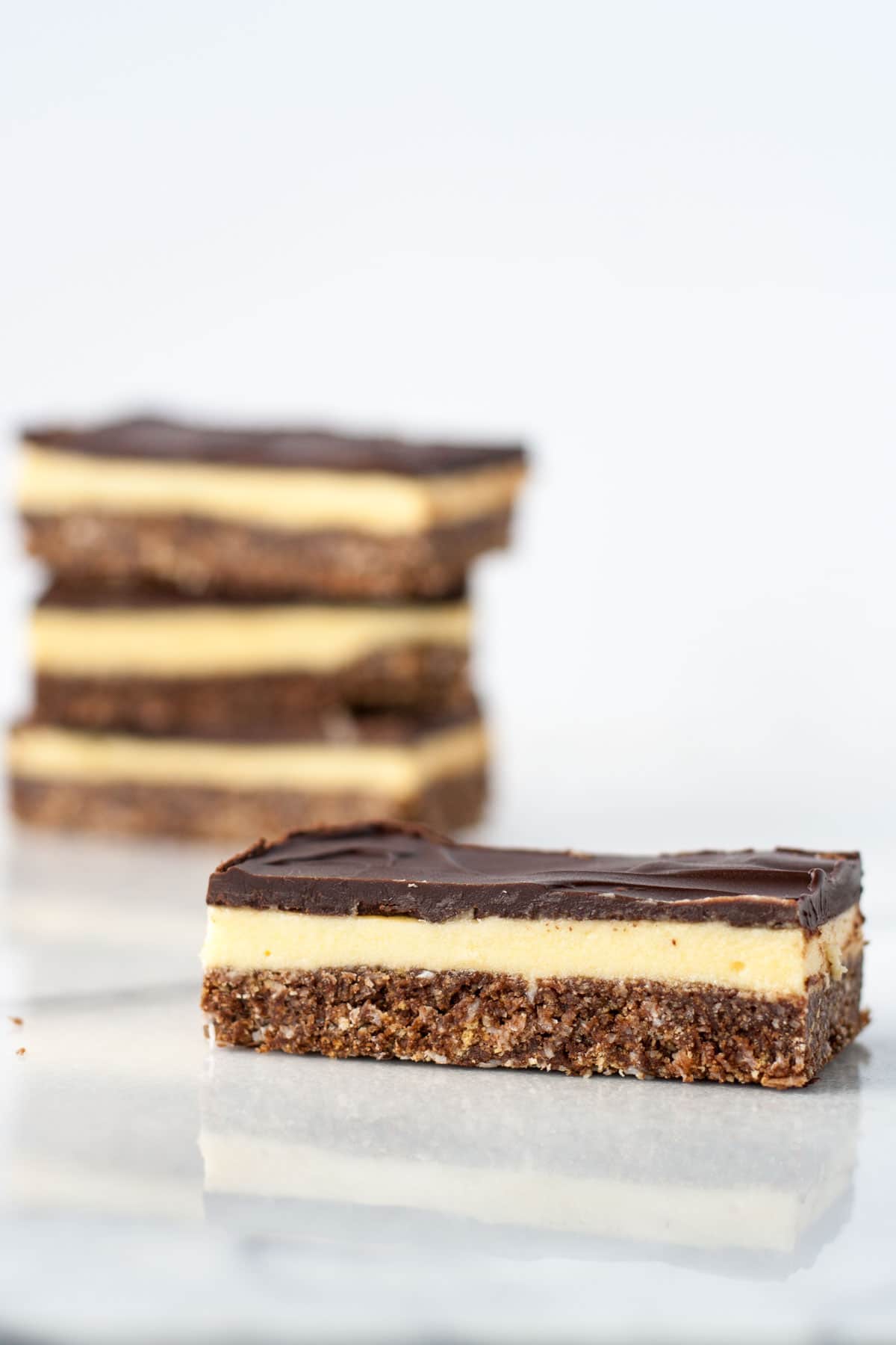 Nanaimo bar in the foreground with a stack of three in the background.