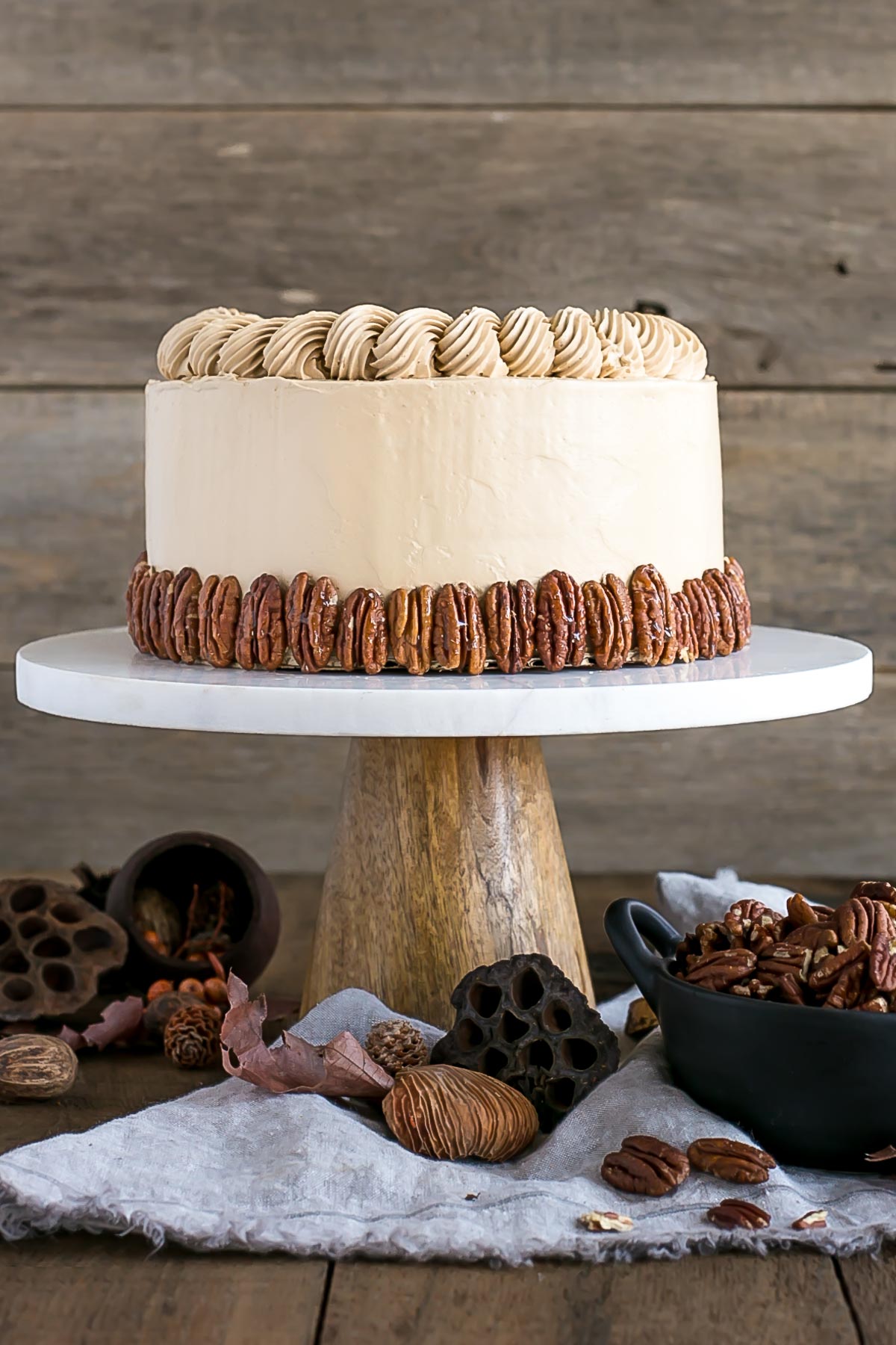 Cake on a marble cake stand with fall decor around.