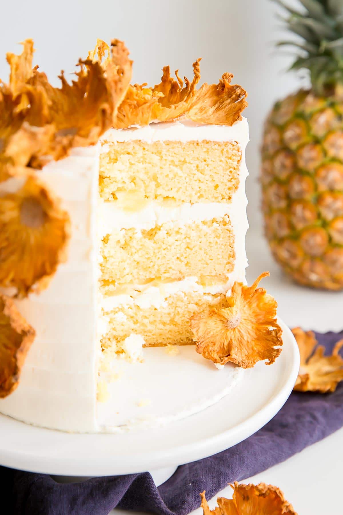 Cross-section image of a pineapple cake showing the cake layers, frosting, and fresh pineapple.