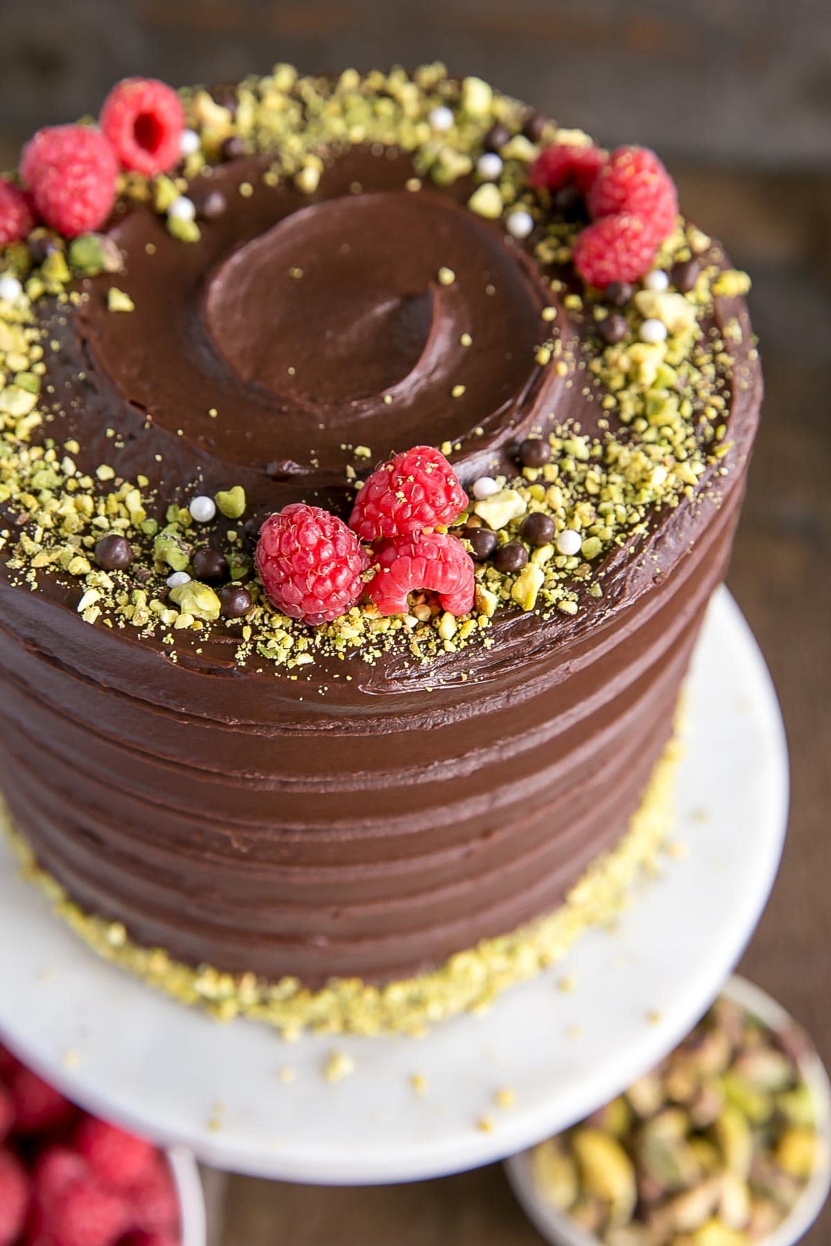 Close up of a Pistachio Cake with fresh raspberries and chopped pistachios.