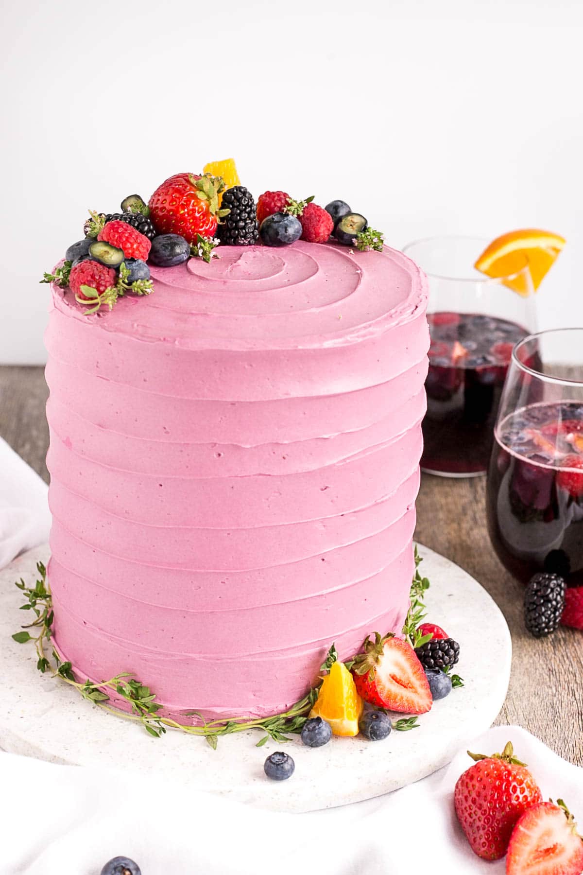 Cake on a white cake plate with sangria in glasses in the background.