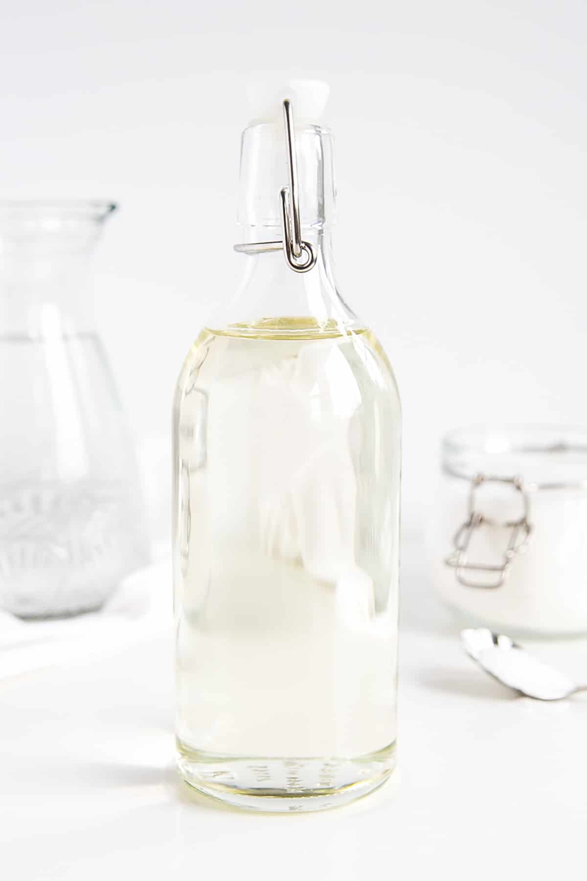 A bottle of homemade simple syrup -- sugar and water in the background.