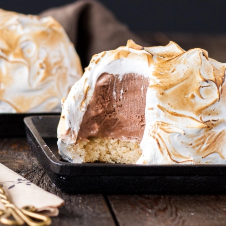 Baked alaska on a black plate.