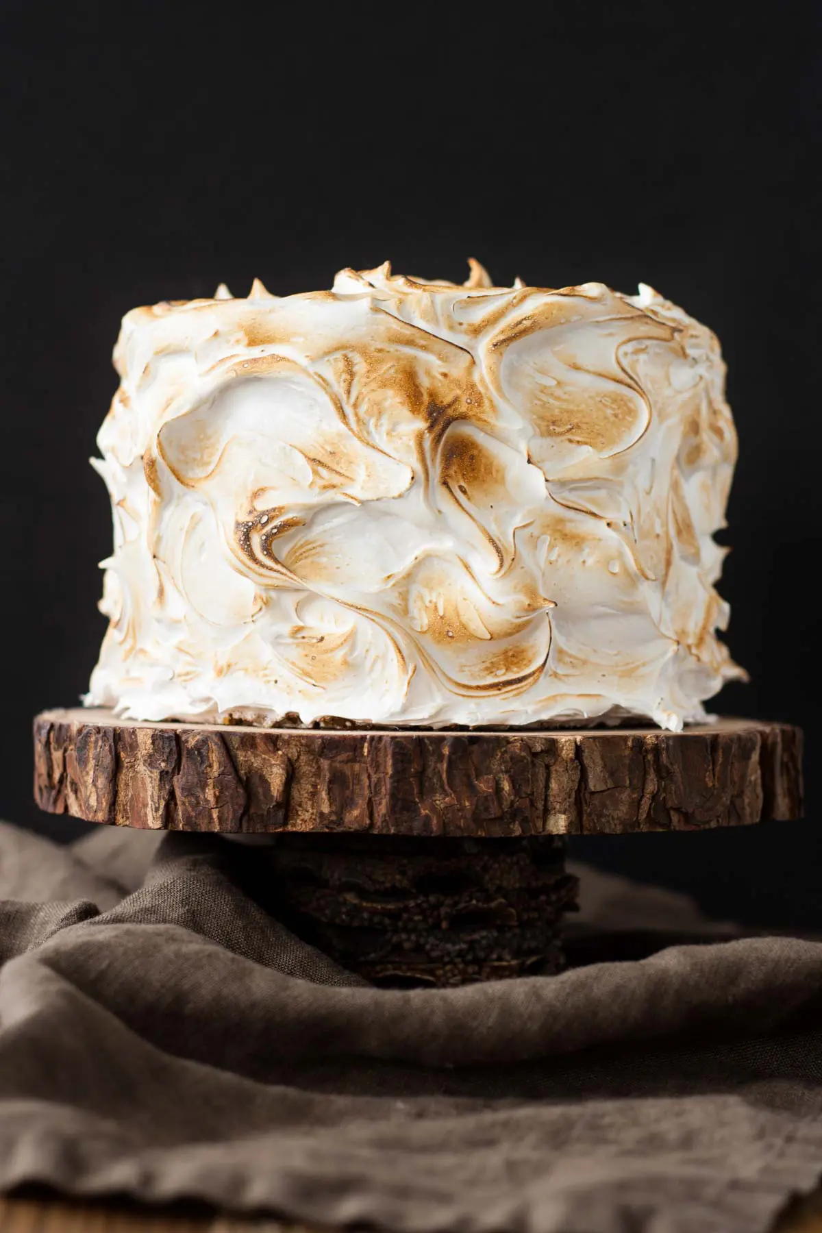 Cake on a wood cake stand on a black background.