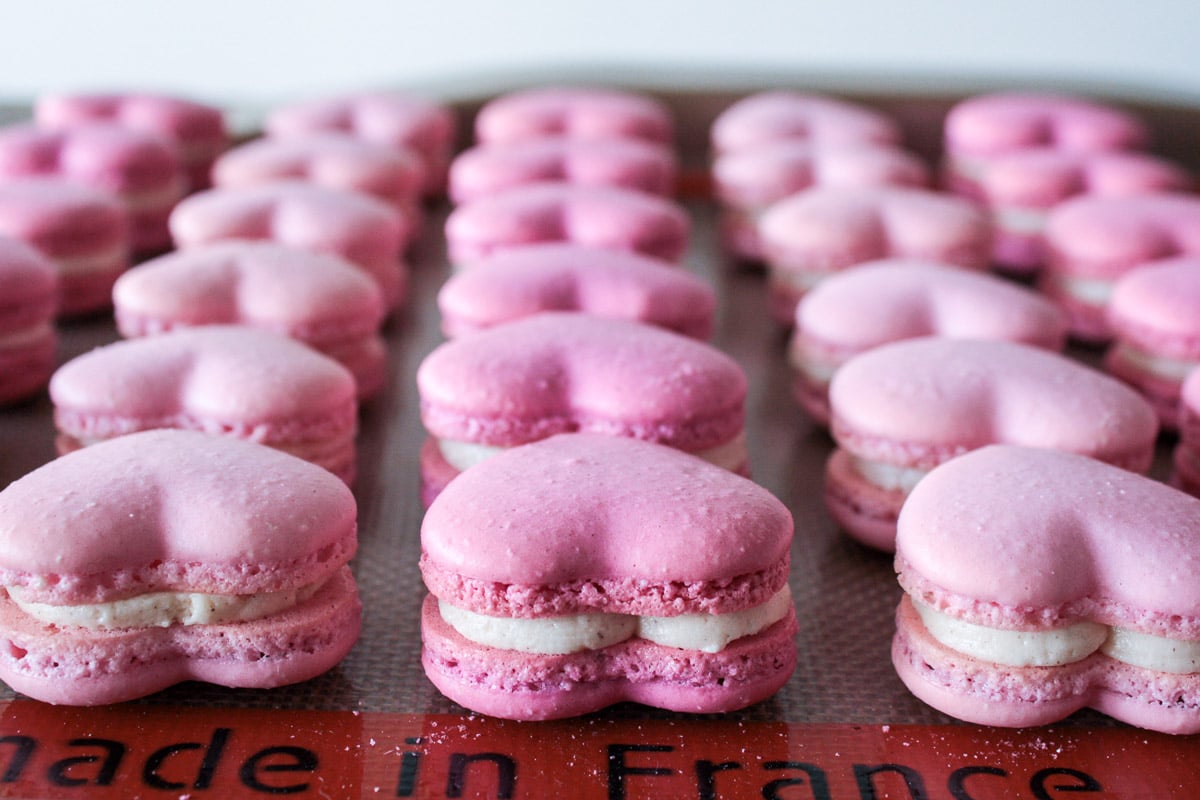 Sandwiched heart macarons on a baking sheet.